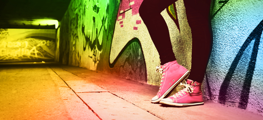 Photo: feet in pink sneakers leaning against a colorful graffiti wall.