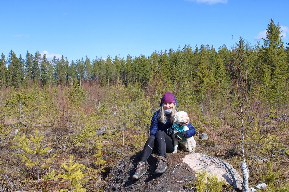 Nainen koiran kanssa metsässä.