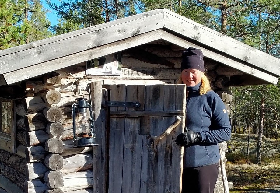 Nainen mökin ovella.