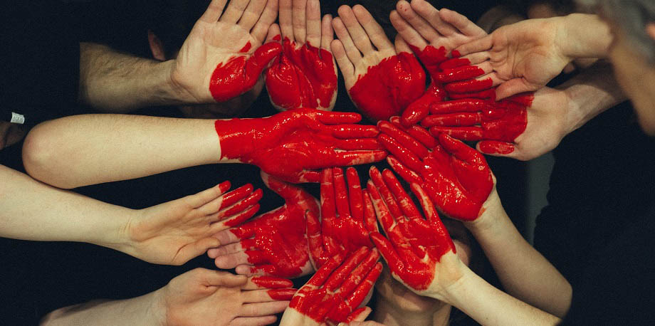 Käsiä, joihin maalattu punainen sydän.