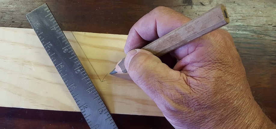 Käsi piirtää viivaa viivottimella.