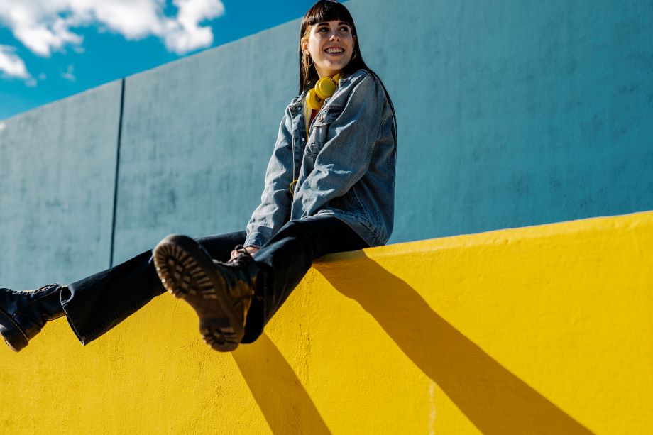 Nuori nainen istuu keltaisen muurin päällä.