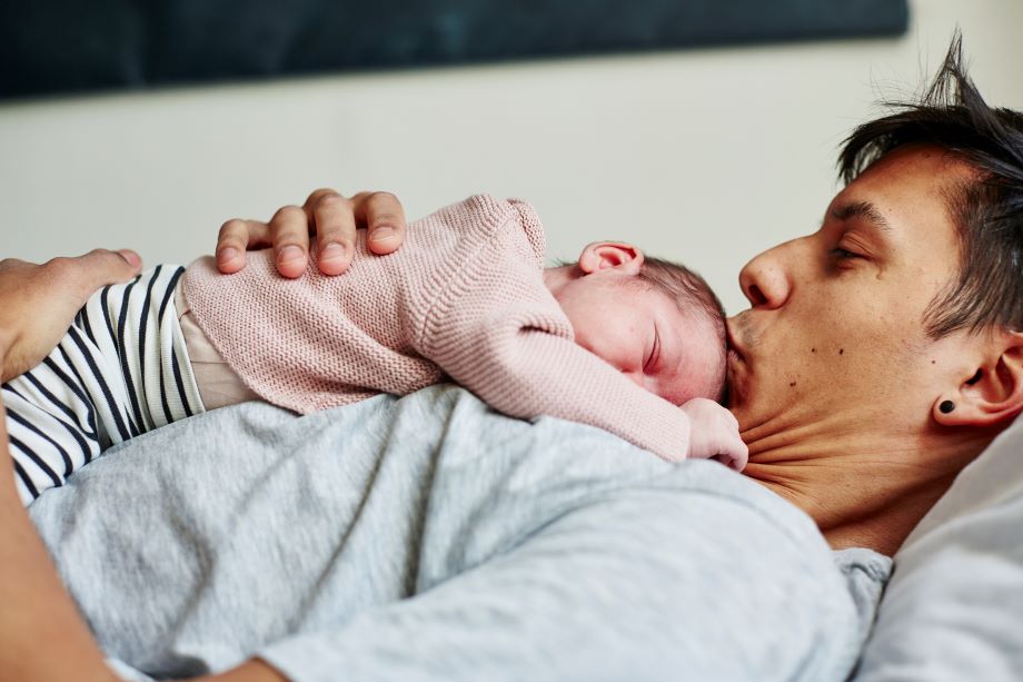 Mies pitelee sylissä pientä vauvaa.