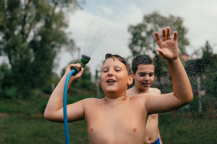 Kaksi poikaa leikkii vesisuihkulla.