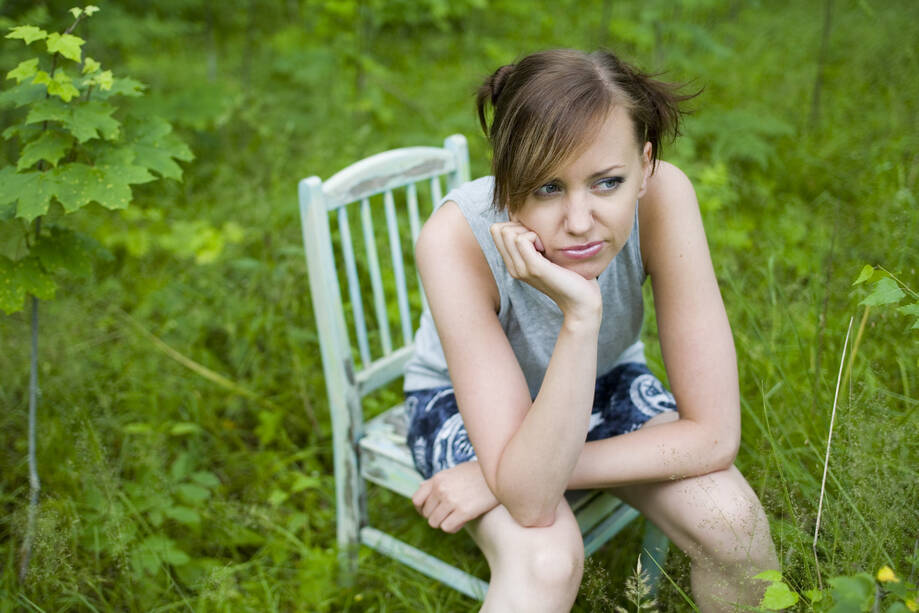 Ikävystynyt tyttö istuu tuolilla.