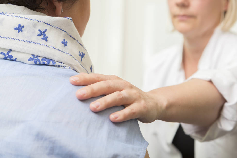 Henkilö koskettaa toista olkapäähän.