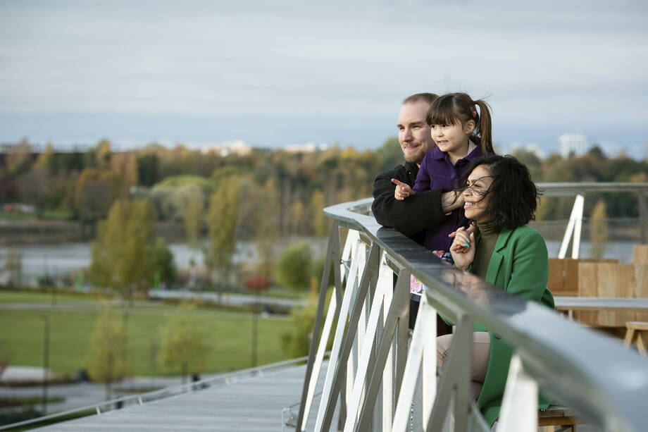 Monikulttuurinen perhe katselee maisemia sillalla. 