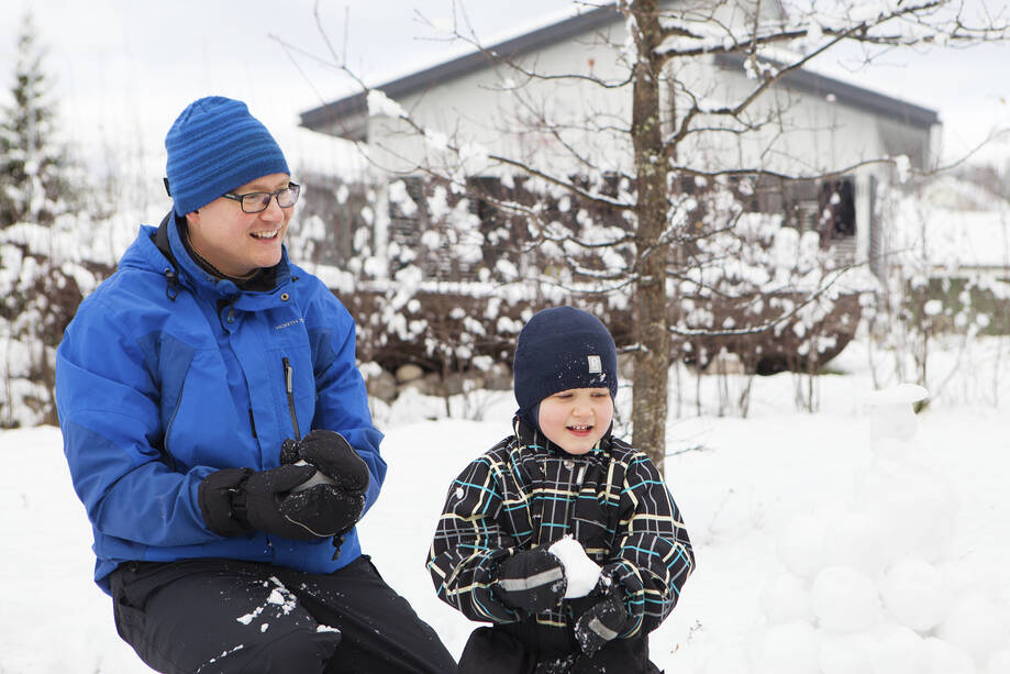 Aikuinen ja lapsi tekevät lumipalloja.
