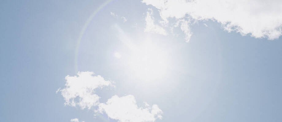 Kuvassa aurinko paistaa siniseltä taivaalta.