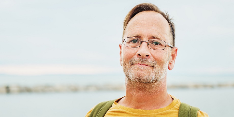 Keski-ikäinen henkilö katsoo kameraan rauhallinen ilme kasvoillaan.