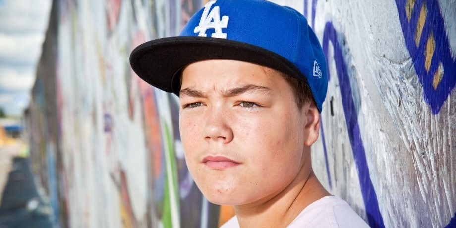 Lippispäinen nuori katsoo vakavana kaukaisuuteen.