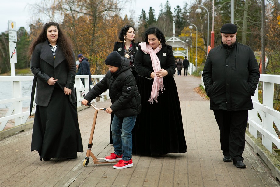 Romaniperhe kävelyllä. Kuvassa kolme naista,yksi lapsi skootilla ja yksi mies.