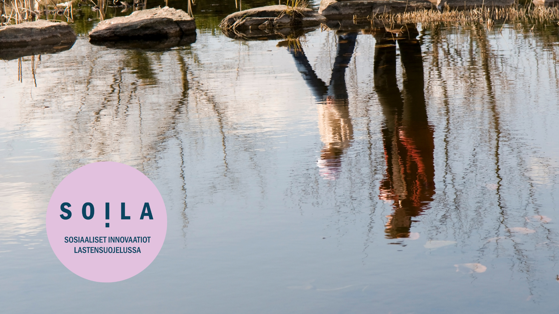 Heijastus vedestä, kaksi henkilöä rannalla. SOILA-hankkeen tunniste.