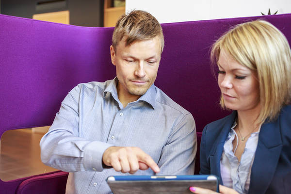 Mies ja nainen käyttävät tablettitietokonetta.