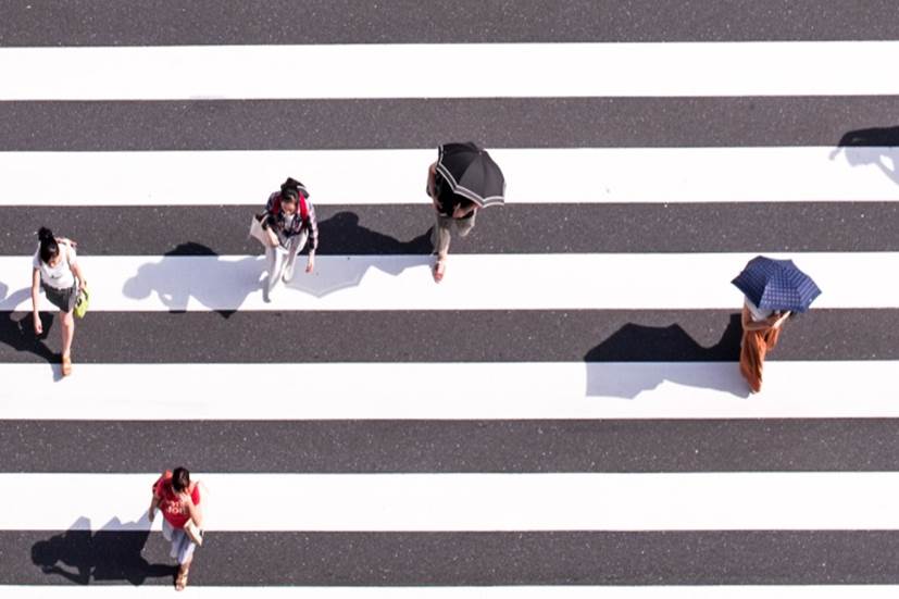 Suojatie ylhäältä päin, kuvassa 5 ihmistä, joilla kahdella on sateenvarjot.