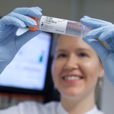 laborantti katsoo hymyillen näyteputkea.