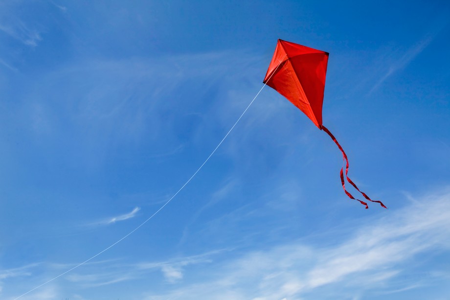 Tuuli-hankkeen tunnuskuva. Punainen leija sinisellä taivaalla.