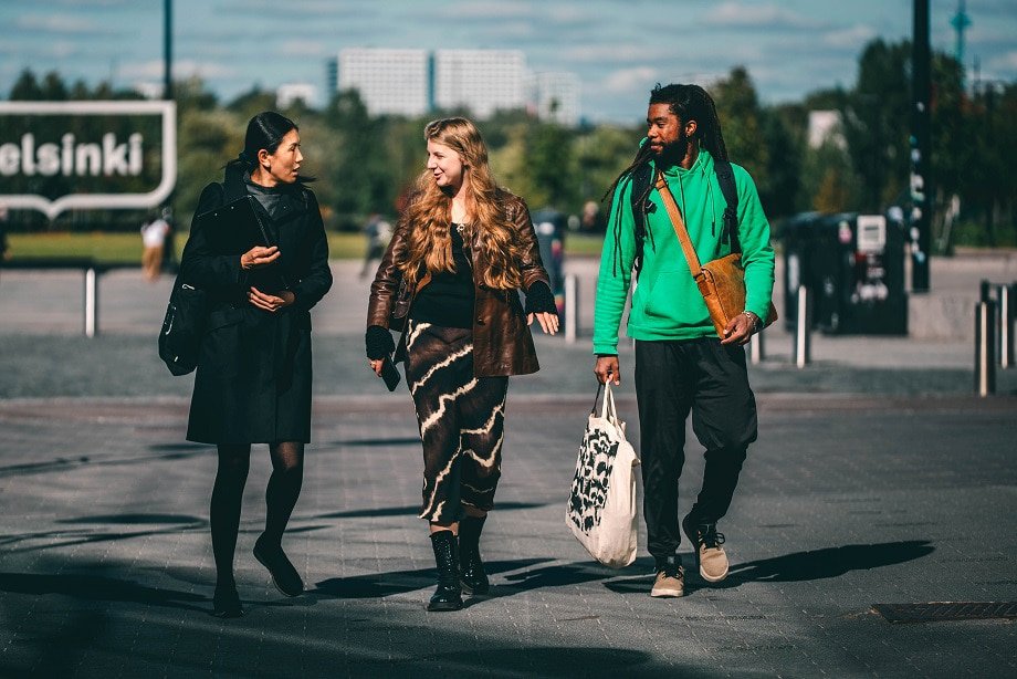 Kolme ihmistä kävelee kaupungilla.