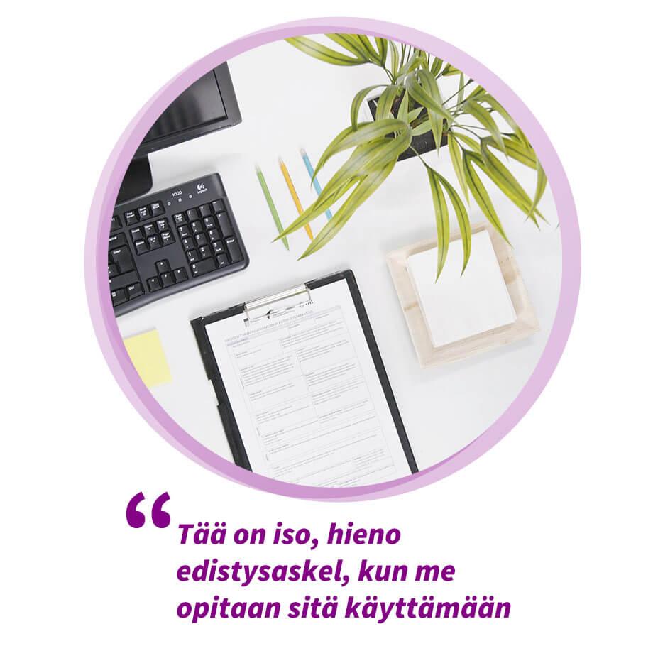 Työpöytä, jolla on tietokoneen näppäimistö, lomake ja viherkasvi. Sitaatti sivun videolta:  Tää on iso, hieno edistysaskel, kun me opitaan sitä käyttämään.