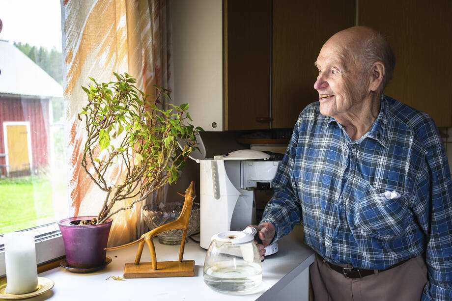 An older man at home making coffee.