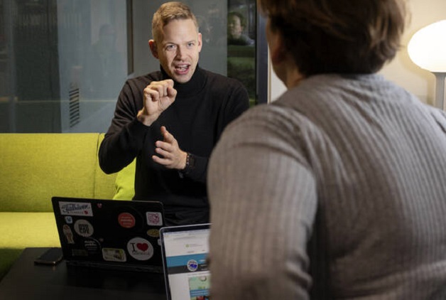 Nuori mies viittoo kokouksessa naiselle.