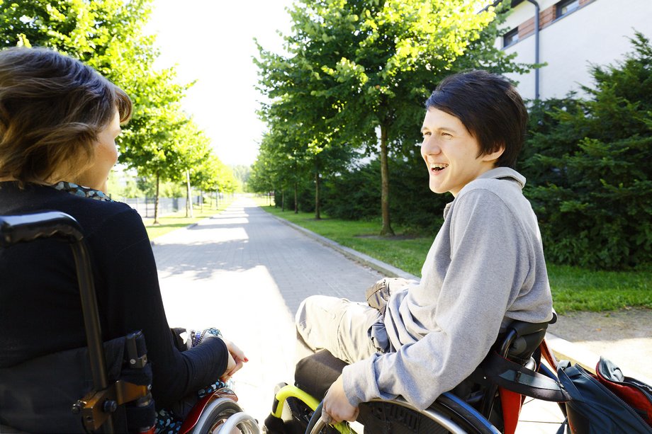 Kaksi pyörätuolia käyttävää nuorta kesäisessä maisemassa.