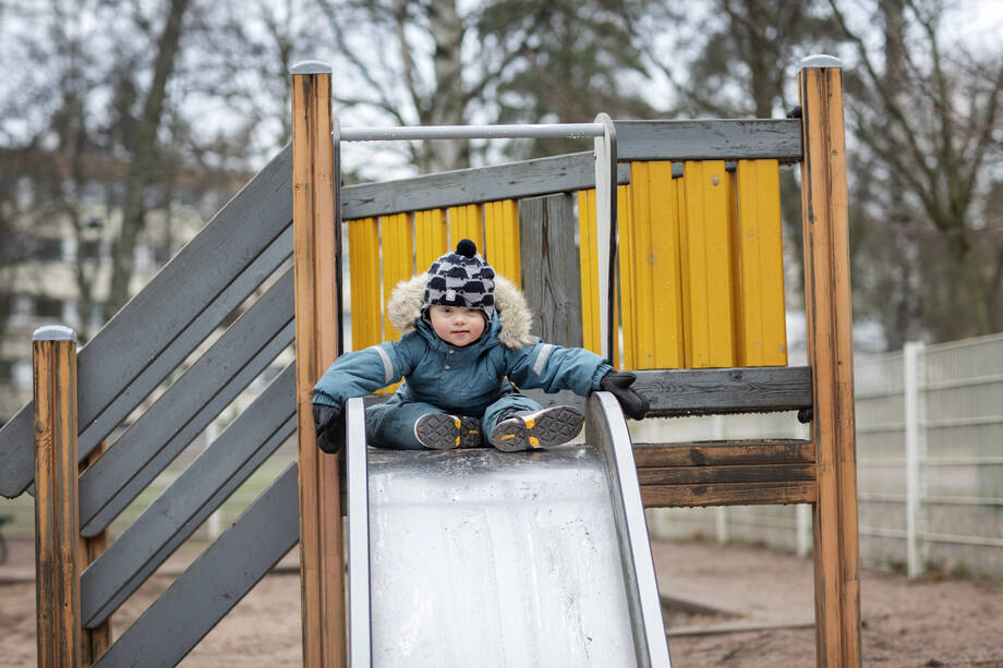 Lapsi leikkipuistossa lähtemässä laskemaan liukumäkeä.