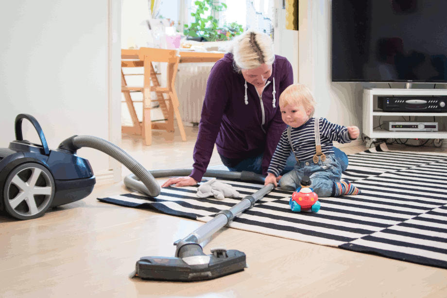 Mother and child doing housecleaning with a vacuum cleaner.