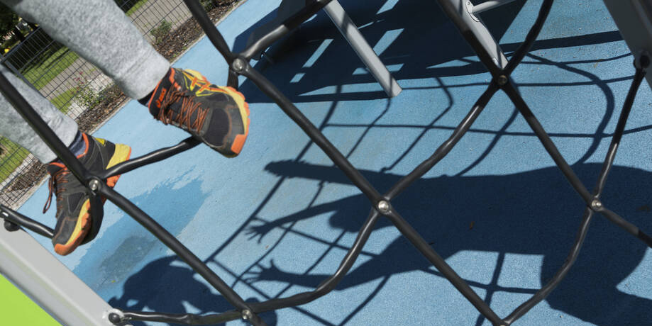 Kuvassa kiipeilytelineen verkko ja lapsen jalat.