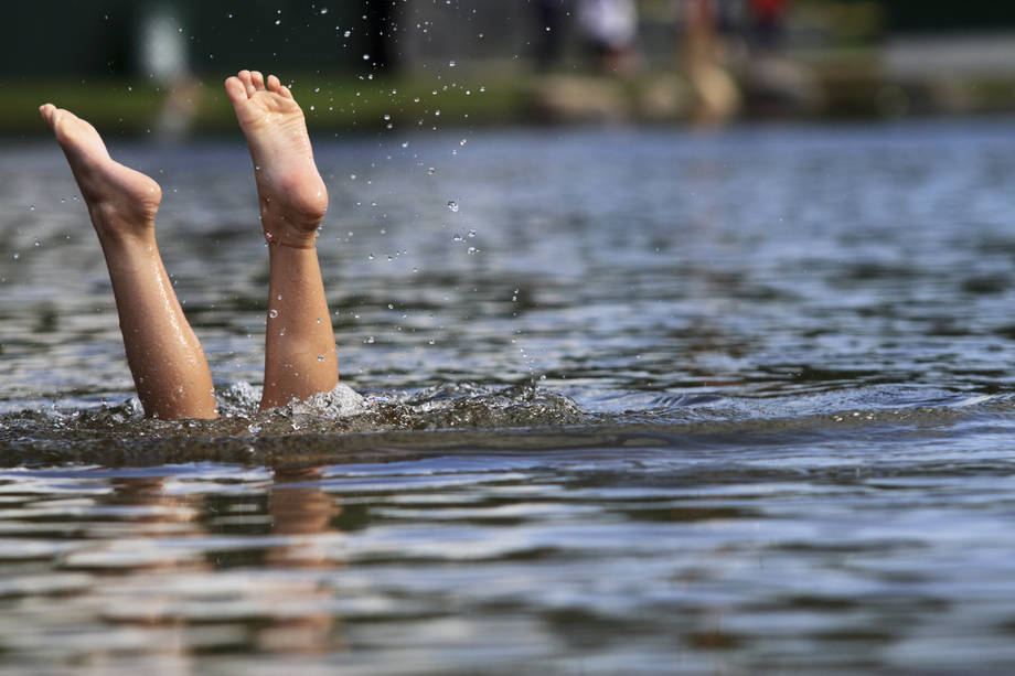 Veteen hyppäävän henkilön jalat pinnan yläpuolella.