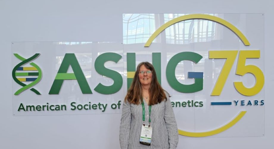 Biopankin työntekijä poseeraa ASHG-kokouksen logon edessä.