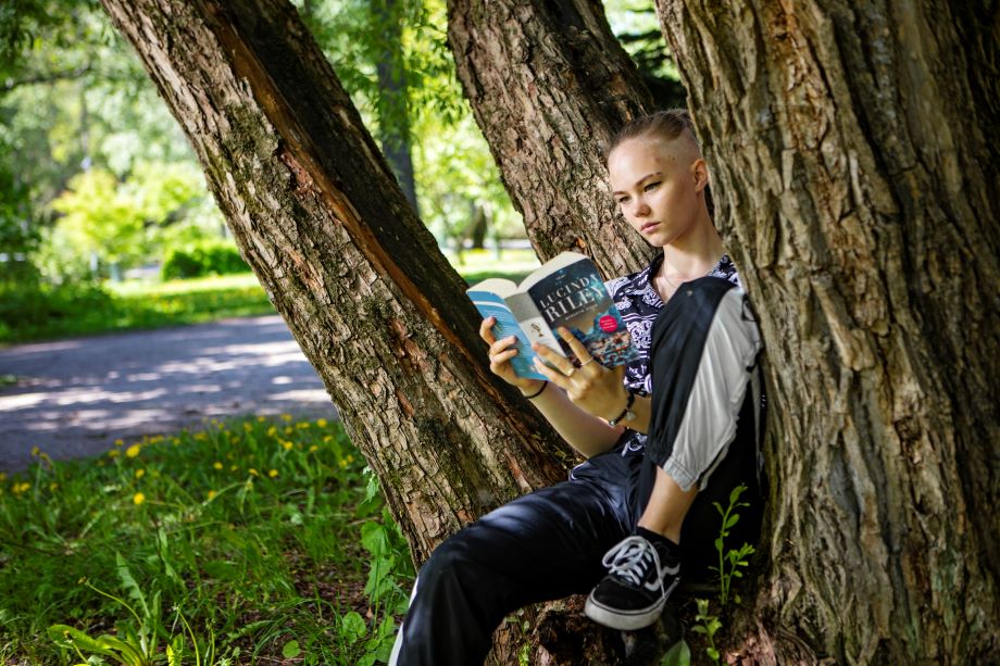 Nuori lukee kirjaa puunkolossa.