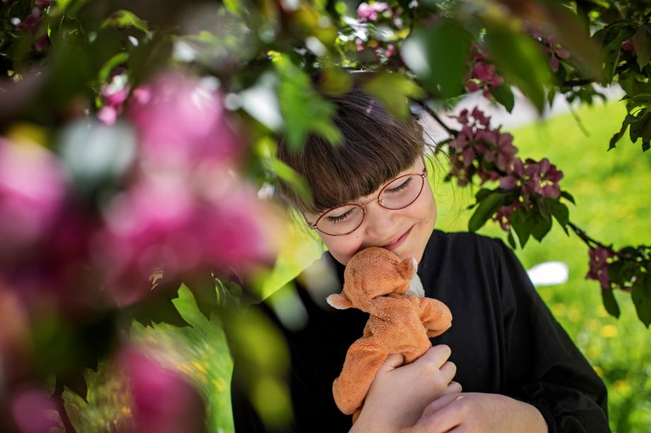 Lapsi halaa pehmolelua puun alla. 