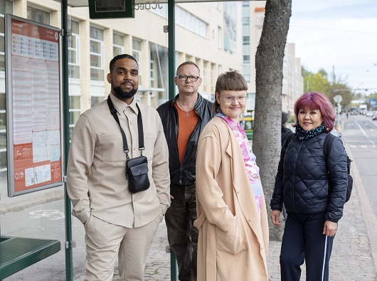 Kuvituskuva: moninaisia kunnan asukkaita bussipysäkillä.