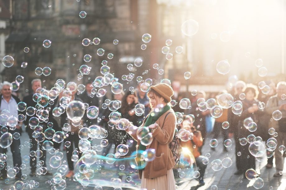 A person is on a street surrounded by soap bubbles.
