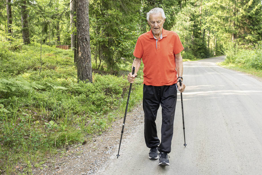En äldre man promenedar med gångstavar.