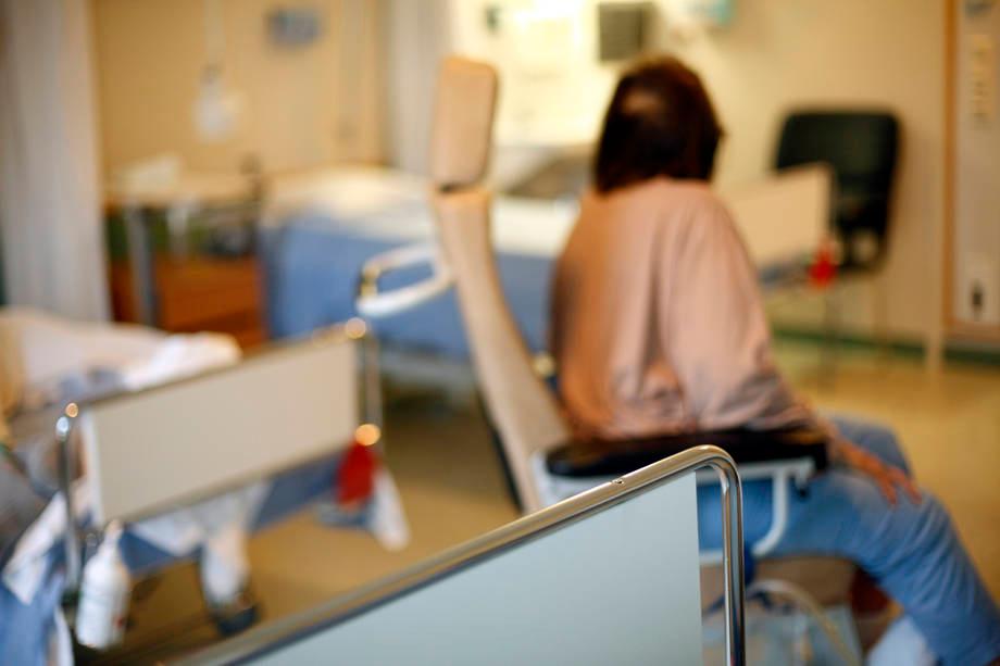 Vanhus istuu sairaalasängyn päällä.