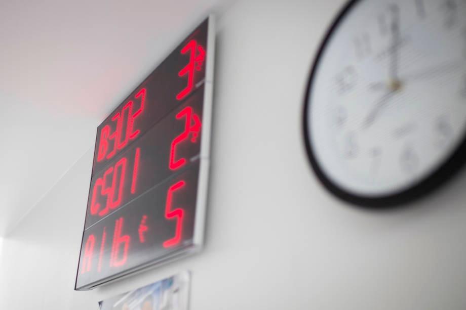 Käytävän seinä, jossa kello ja jonotusnumerotaulu.