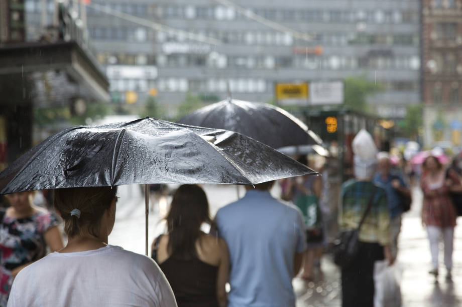 Ihmisiä kävelemässä kadulla sateenvarjojen kanssa.