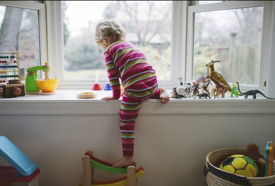 lapsi kiipeää ikkunalaudalle.