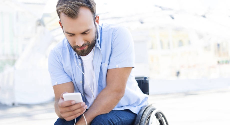 mies katsoo kännykkää kuulokkeet päässä.