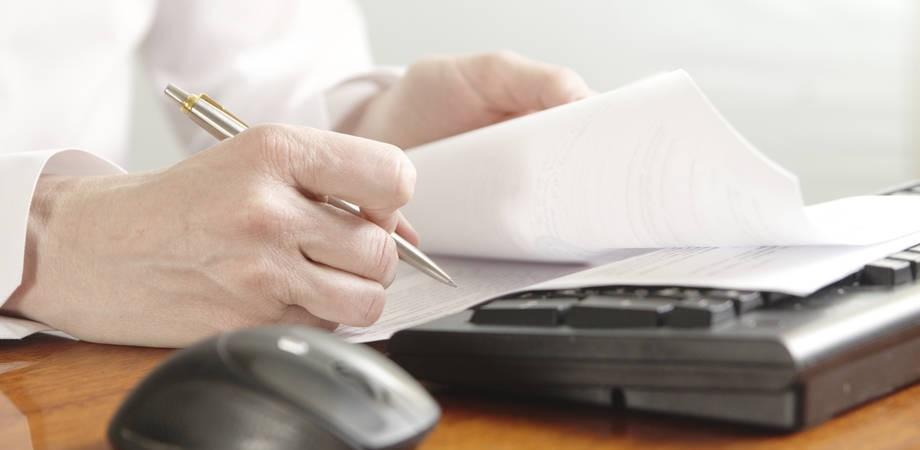 kynä, papereita ja näppäimistö.