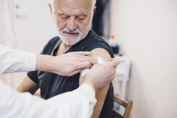 Vaccinatören sätter plåstret på den vaccinerade.