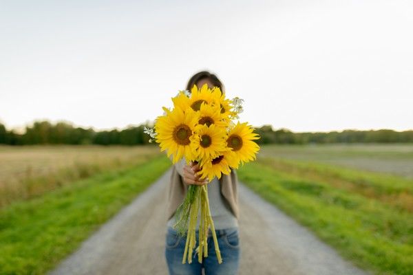 Woman is holding a bouquet of sunflowers.