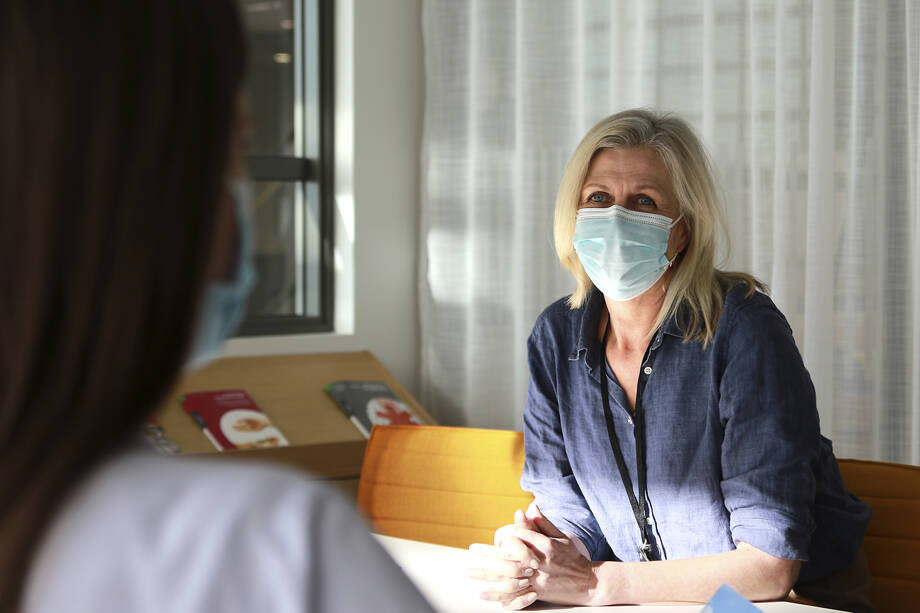 Två kvinnor pratar, de har ansiktsmasker som skydd.