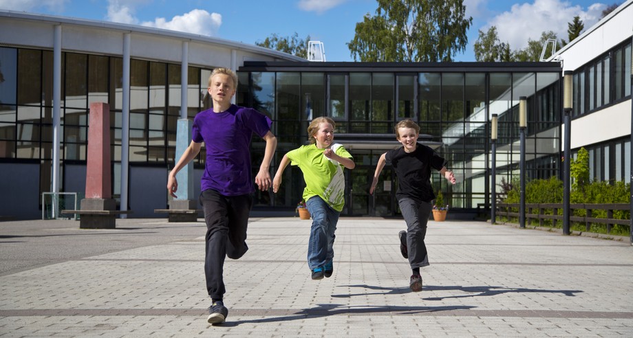 Tre pojkar springer på skolgorden