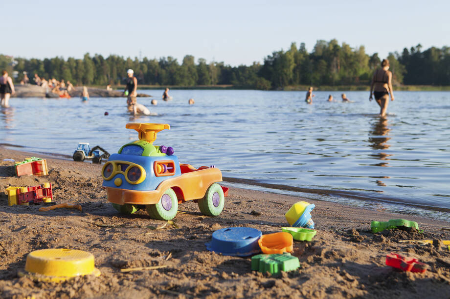 Plastleksaker och många människor på en solig strand. 