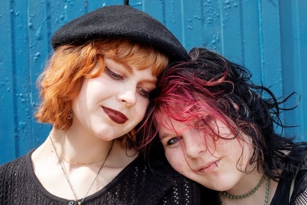 Två ungdomar lutar sig mot varandra.