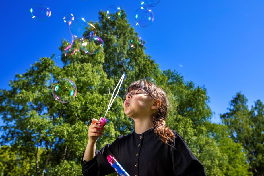 Barnet blåsar såpbubblor.