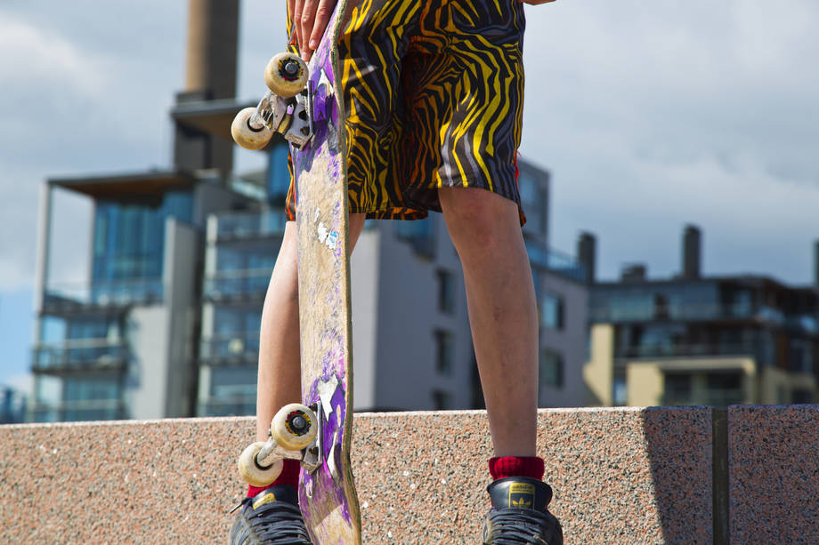 En ungdom står med ett skateboard i handen.